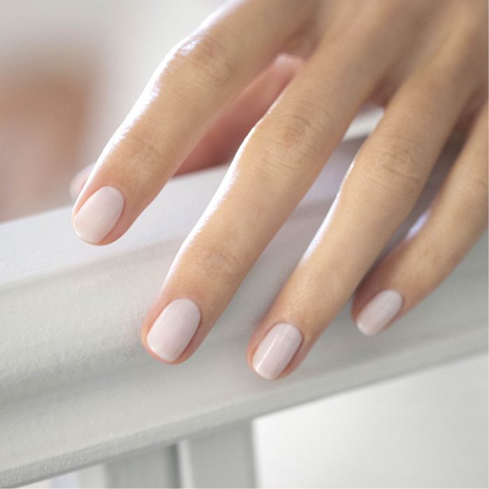 A hand holding a rail wearing nude nail varnish